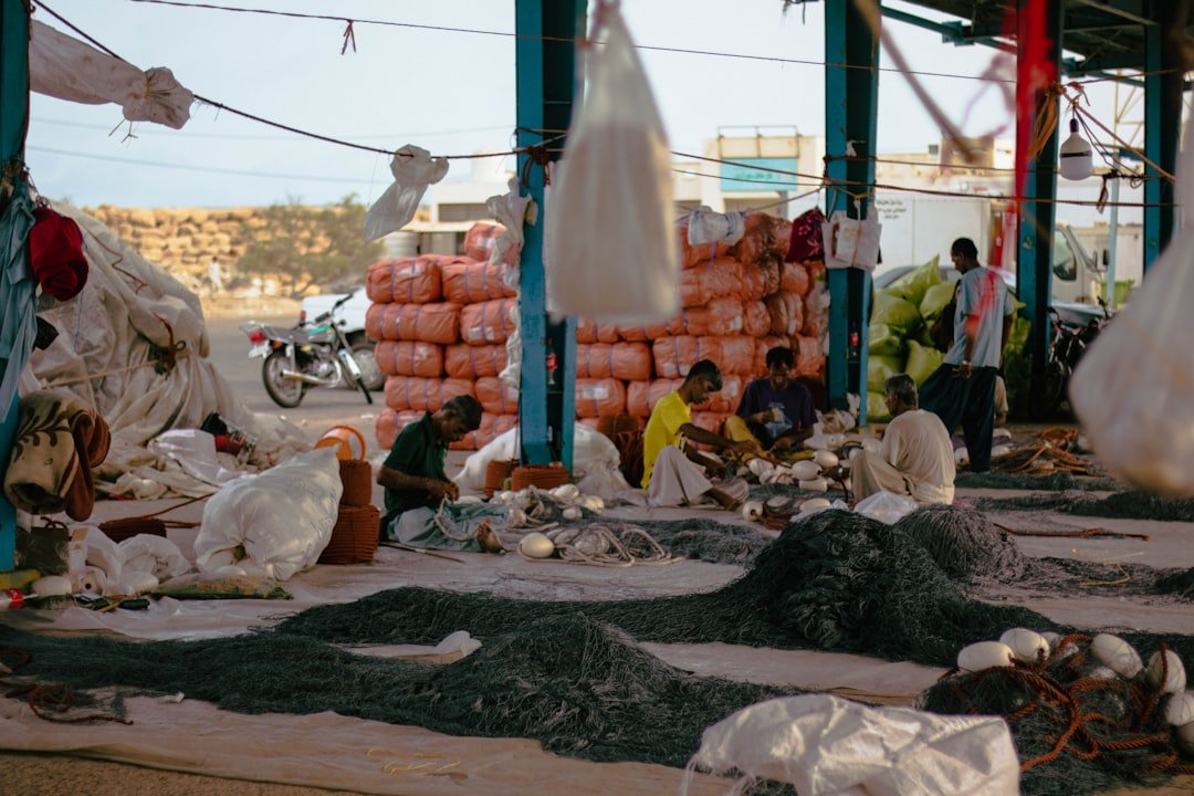 People working at a coastal fish market with nets and fresh catch, illustrating the livelihoods tied to Gwadar's fishing economy