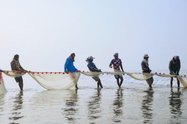 Fishermen pulling a large fishing net from the sea, representing Gwadar's coastal fishing community