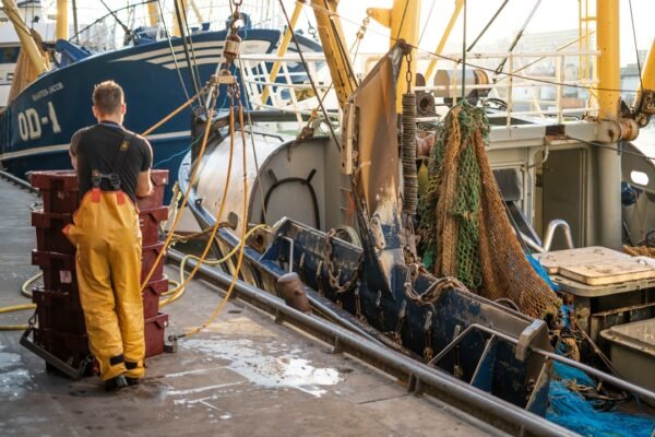 A fisherman standing beside his boat, representative of the boat registration and inspection drive underway along the Gwadar coast