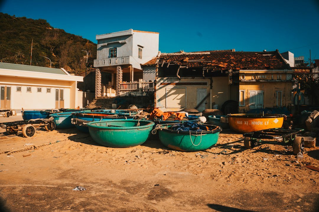 Small fishing boats resting on a sandy shore near coastal buildings, representative of fishing communities in Pasni and Pishukan
