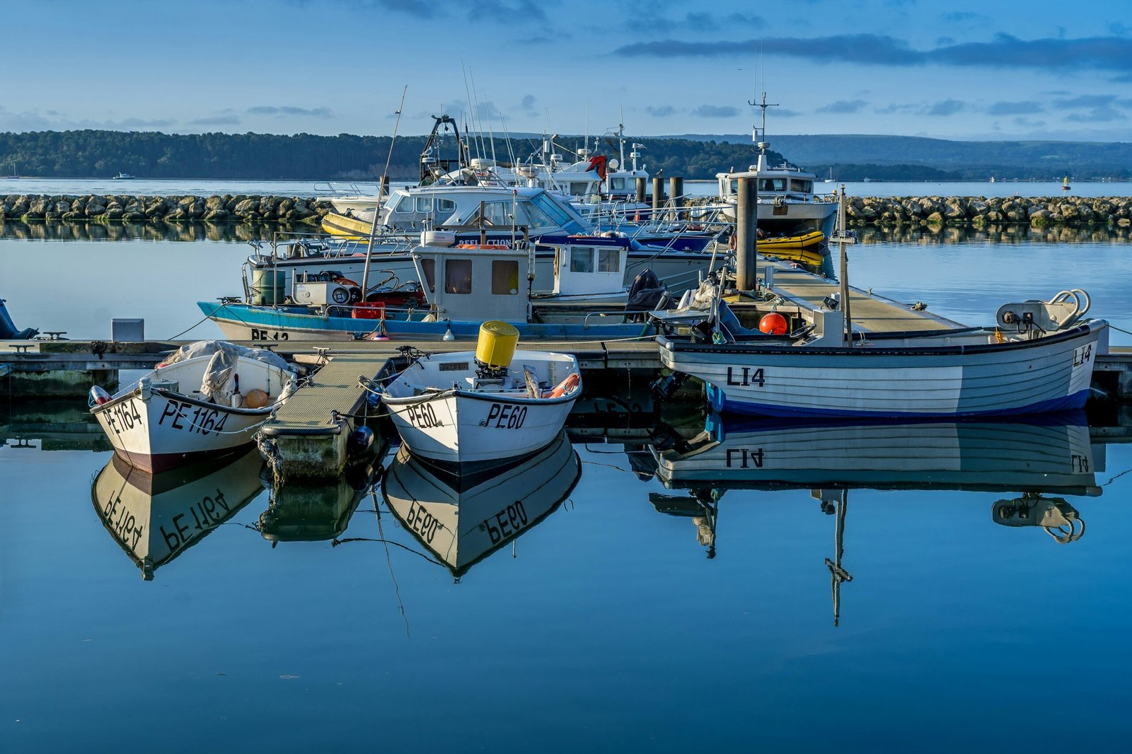 Fishing boats reflected in calm harbor waters, representative image for the paved boat platforms GDA has approved for Gwadar's fishermen