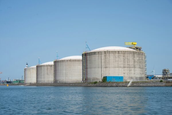 Industrial gas storage tanks by the water under a clear sky, representative image for the $14bn Tri-State Gas Terminal planned for Gwadar