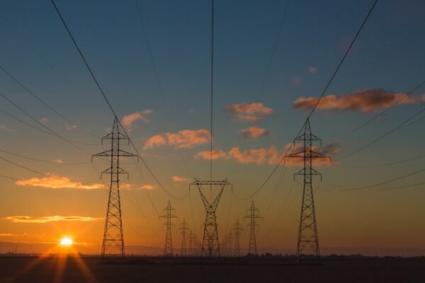 Electricity transmission pylons silhouetted at sunset, representative image for Gwadar's cross-border power supply from Iran