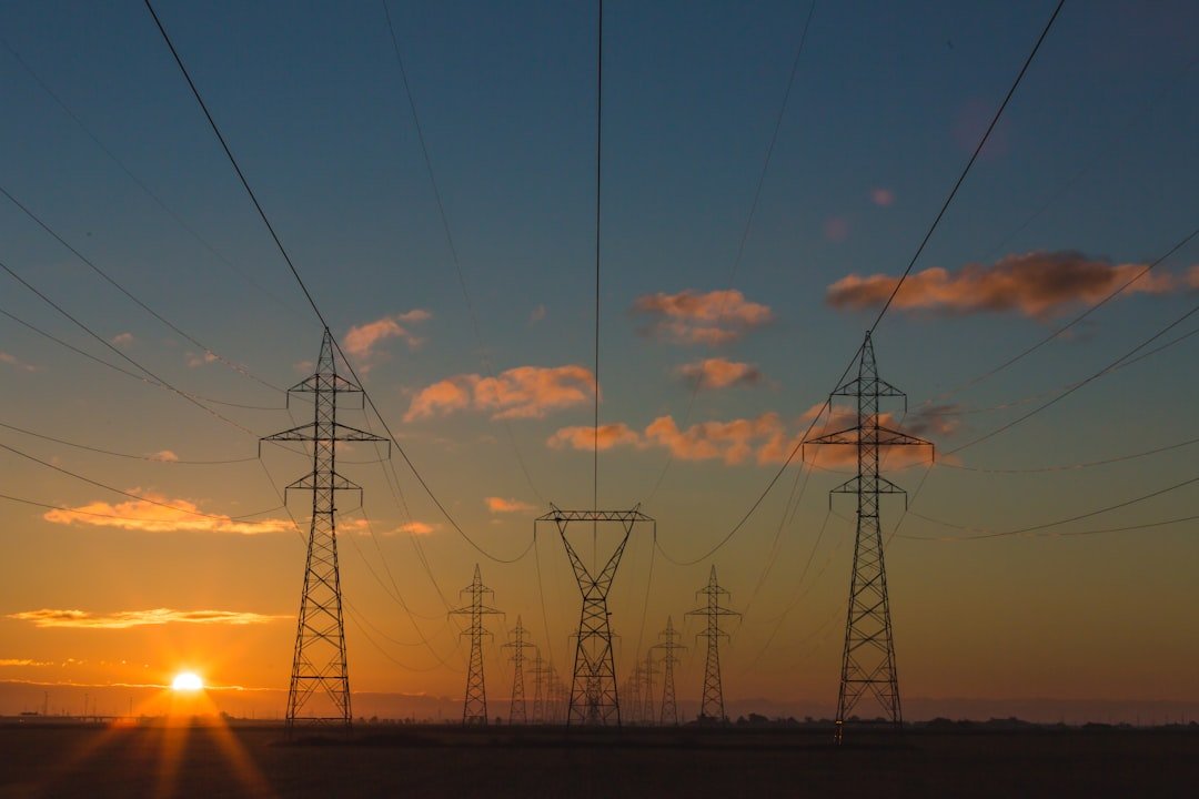 Electricity transmission pylons silhouetted at sunset, representative image for Gwadar's cross-border power supply from Iran