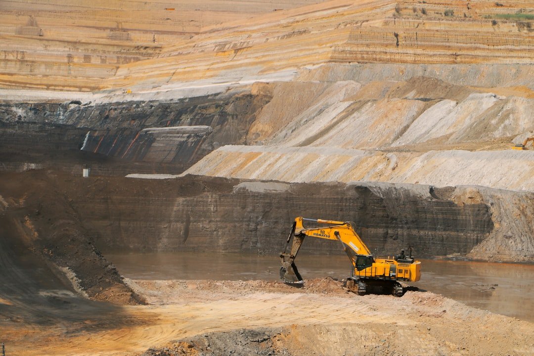 A yellow excavator working in a large open-pit mine, representative image for construction activity at the Reko Diq copper-gold project
