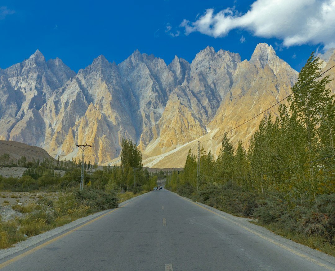 A remote road leading toward jagged mountains under a clear sky, representative image for the isolated highway network linking Gwadar district to the Pakistan-Iran border