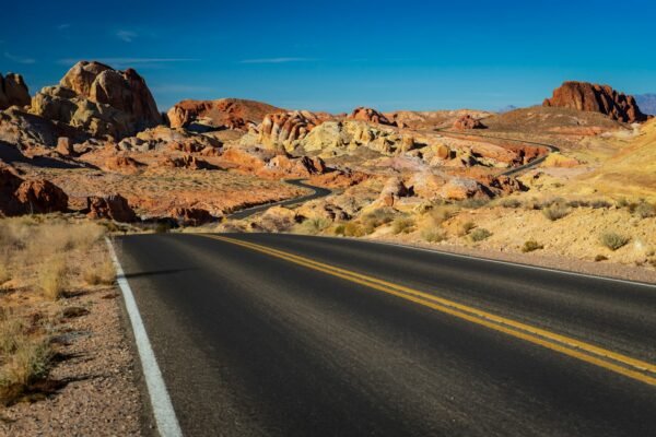 Asphalt highway cutting through arid brown mountains, representative image for CPEC Western Route road projects in Balochistan