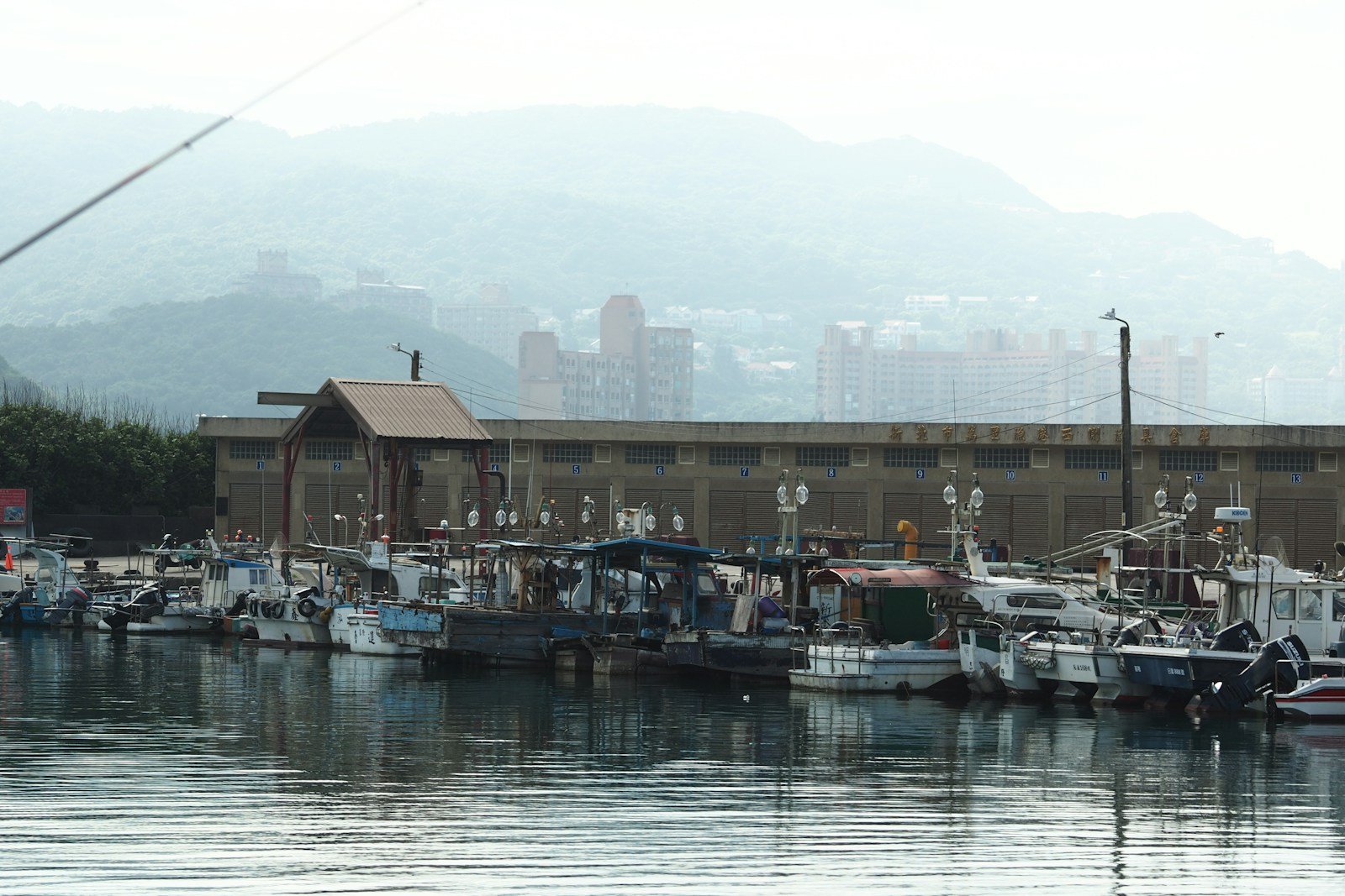 Fishing boats docked in a harbor with misty mountains, representative image for Gwadar's fishing community and fisheries welfare projects
