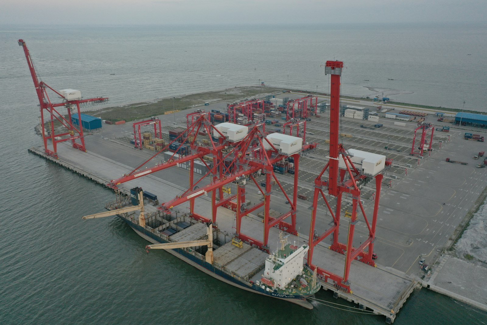 Cargo ship docked at a port with large gantry cranes, representative image for the Gwadar-Sohar sister port cooperation between Pakistan and Oman