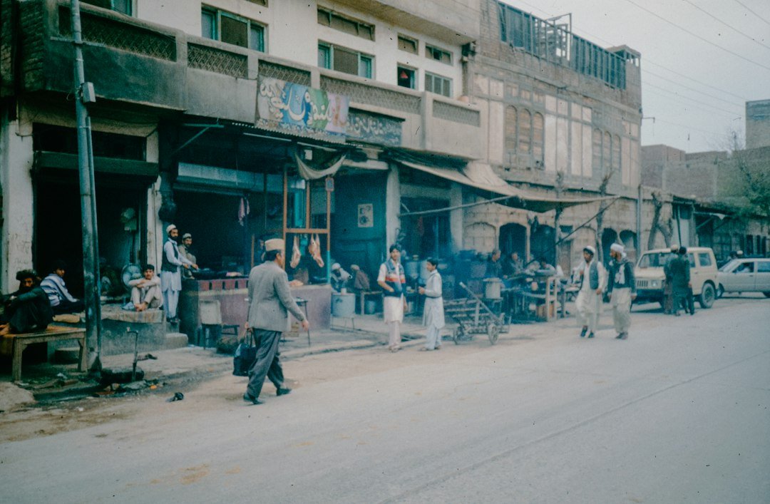 Pedestrians walk down a street past tall buildings, representative image for the busy public spaces Gwadar's Safe City cameras are meant to cover
