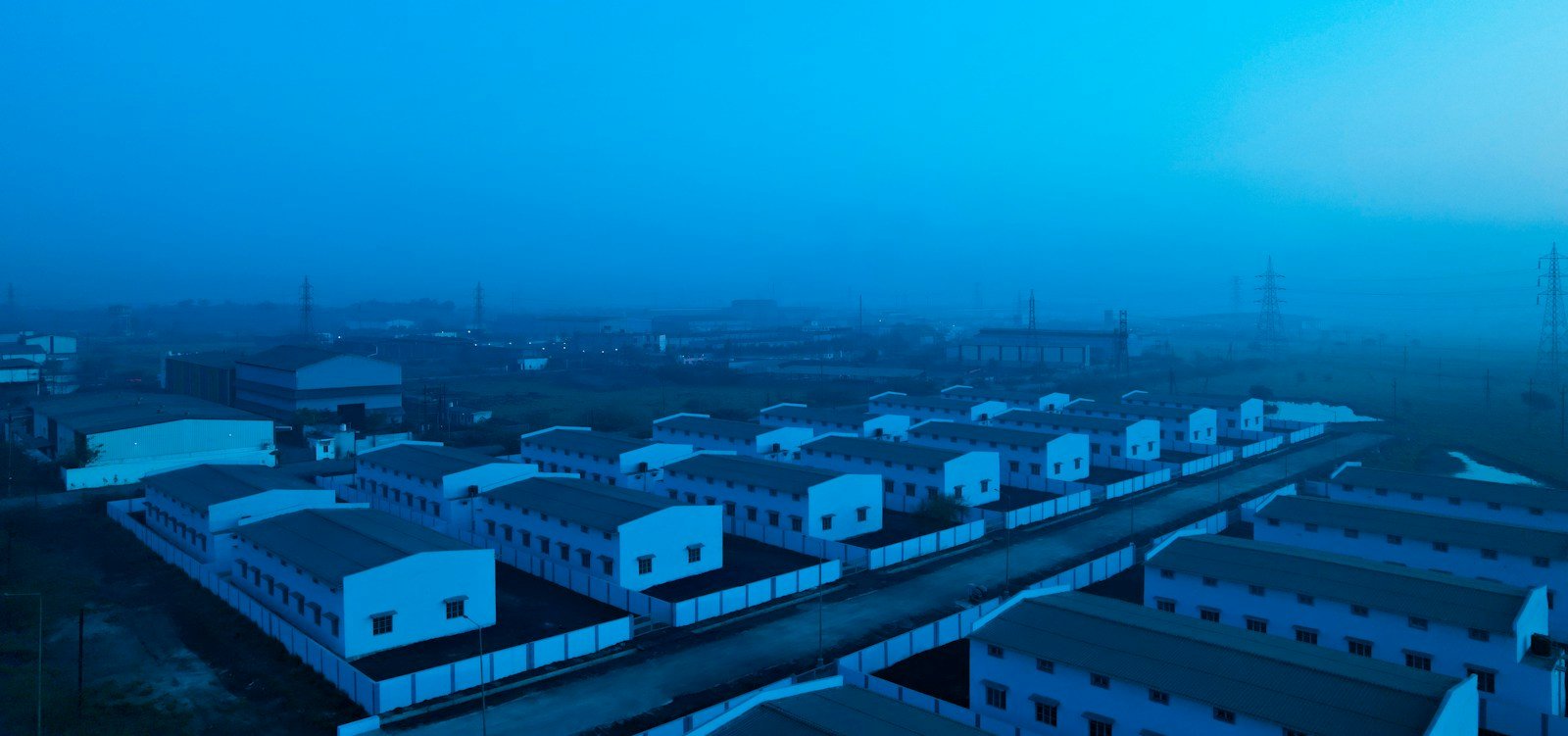Aerial view of an industrial zone with rows of warehouse buildings and wide access roads, representative image for Gwadar Free Zone's warehousing and industrial plots