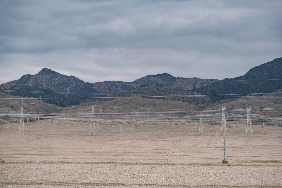 Power transmission lines running across an arid desert landscape with distant mountains, representative image for electricity infrastructure projects in Balochistan